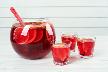 Glasses and bowl with aromatic punch drink on white wooden table