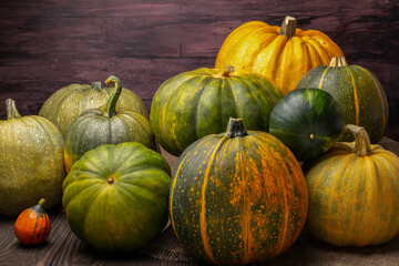 many pumpkins of different size and color on a dark wooden background