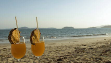 Cocktail Pina Colada, in slice pineapple, at sunset. Blur background beach and sea. Concept resting tropical tourism summer holidays, food and drink, alcohol beverage