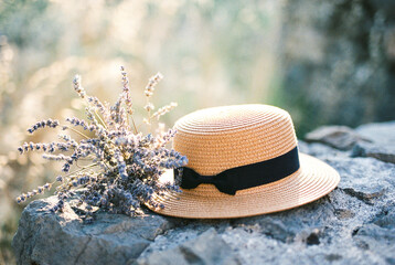 Lavender bouquet next to a straw hat on stones