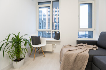 Living room interior in gray and brown colors features gray sofa atop dark hardwood floors facing stone fireplace