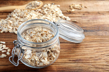 Glass jar with oatmeal on wooden table. Space for text