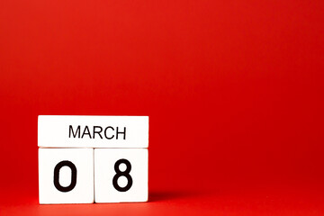 Calendar with white wooden date made from cubes. March 8. International Women's Day. Red background 