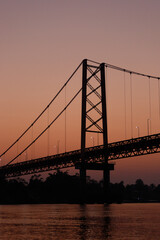 Fototapeta premium Puente Billinghurst at Rio Madre de Dios in Puerto Maldonado in the Tambopata National Park in Amazonas region as seen during spectacular orange sunrise (Peru, South America)