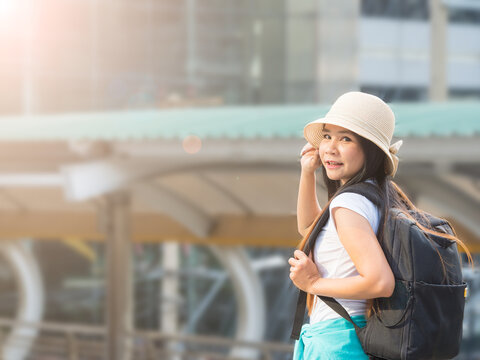 Woman traveller with backpack and hat travelling alone in the city on the sunny day. Holiday concept.