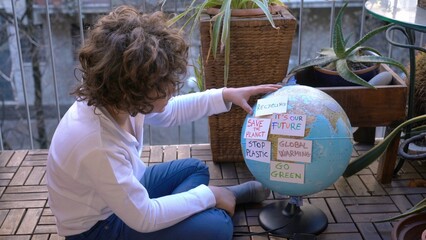 7 years  boy child looking  Earth globe with stickers with the message Save the Planet, Help and No Plastic, Recycling, Concept save our planet and climate change due  global warming - it's our future