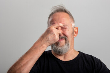 the middle-aged man holds his hand firmly on his nose to plug the horrible smell he is smelling