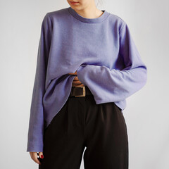 Young woman wearing pastel purple crop sweater and black trousers isolated on white background.