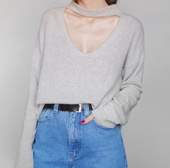 Young woman wearing a light sweater and blue high-waisted mom jeans isolated on white background