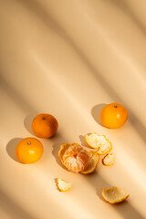 Fresh tangerines under the rays of sunlight on a beige background.