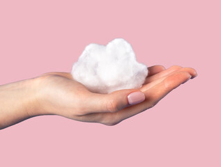 Hand holding cotton cloud at pink background. Dreaming, cloudy weather, climate concept in surrealism style. High quality photo