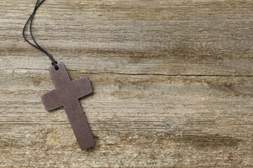 Christian cross on wooden table, top view. Space for text