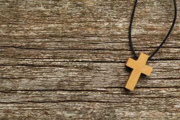 Christian cross on wooden table, top view. Space for text