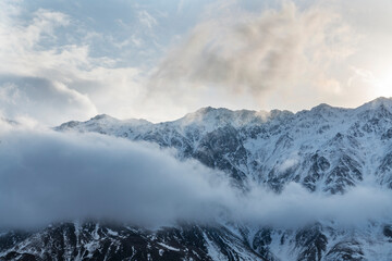 Beautiful winter mountains landscape  High snow covered mountains in the clouds. Georgia, Kazbegi.