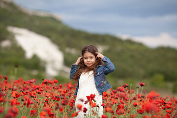 Pretty little girl on a poppy field, outdoor