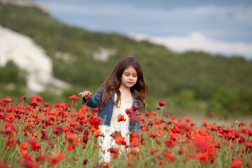 Obraz na płótnie Canvas Pretty little girl on a poppy field, outdoor