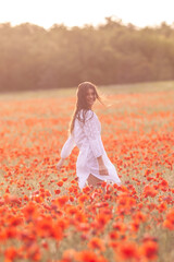 Beautiful girl in a white dress on a poppy field