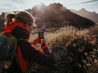 Foto auf Acrylglas Kanarische Inseln Blond girl taking pictures with the smartphone of the hiking sceneries in the national park of Tenerife, Spain. Teide National Park is the biggest park on the Canary Islands. 