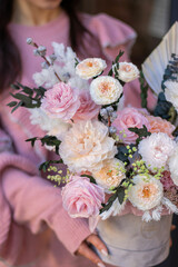 Beautiful spring flowers in box on woman hands. Preserved arrangement in grey round box. Women's day.