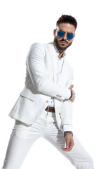 cool bearded businessman with sunglasses holding arms in a fashion pose