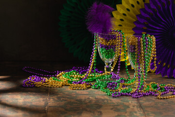 Mardi gras carnivale green, purple, yellow beads on rustic tile background