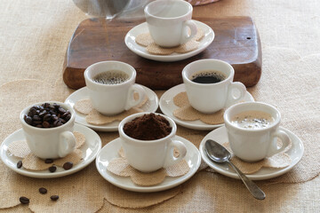 caffee cups with various stages of caffee, coffee beans, grinded coffe and coffee in a cup