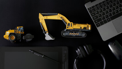 Stylus and graphics tablet, pc mouse, laptop and headphones on black next to models excavator and asphalt roller. Сoncept of designing construction equipment and engineering of landscaping works