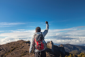 hiker raising his hand with his backpack through rocky mountain landscape with paramo vegetation in...