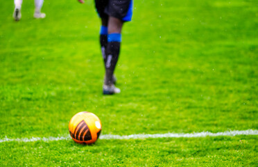 Soccer ball on a soccer field line with player on the background.