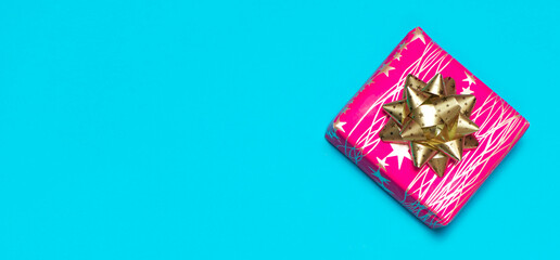 Pink square gift box with gold bow, blue banner with text space, top view