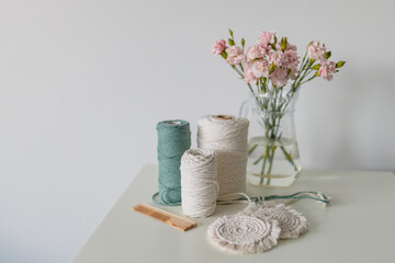 Balls of white and green yarn on white table. Handmade macrame braiding. Female hobby. Selective focus, web banner