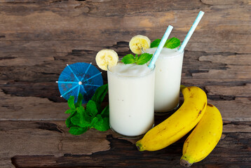 Banana fresh cocktail vanilla smoothies  fruit juice beverage healthy the taste yummy in glass drink episode good morning on wooden background from the top view.