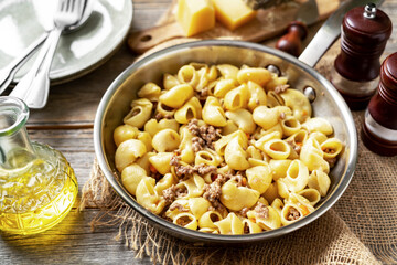 Pasta Pipe Rigate with stew In Bianco in a frying pan on a gray wooden culinary background. Traditional Italian pasta with ground beef on the kitchen table closeup