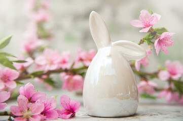Spring blossom, Easter concept, miniature bunny, flowering tree close-up and copy space. Pink natural texture of natural flowering tree. Easter egg and branches of blossoming on an table..