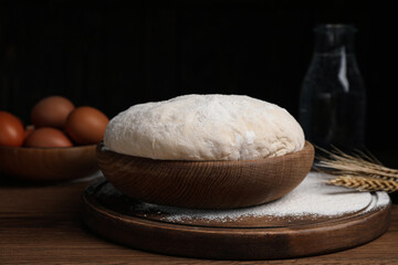 Dough in bowl on wooden table against black background. Sodawater bread recipe