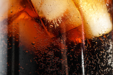 Glass of refreshing soda drink with ice cubes as background, closeup