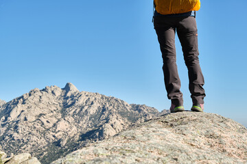 Hiker with a backpack standing on top of a rock and admire the mountains