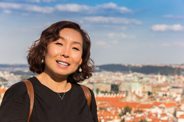 Attractive middle-aged asian woman with dark hair in front of the skyline of Prague