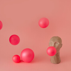  A sculpture of an Asian making balloons out of chewing gum. Balloons are scattered all around on a...