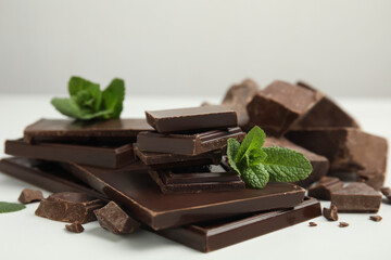 Tasty dark chocolate pieces with mint on white table