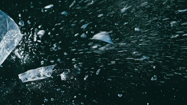 The man breaks piece of ice on the ice. Slow motion. Transparent ice floe is broken on ice with cracks. Shatter to pieces. Frozen Lake Baikal. Winter landscape Natural landmark of Russia. Top view.