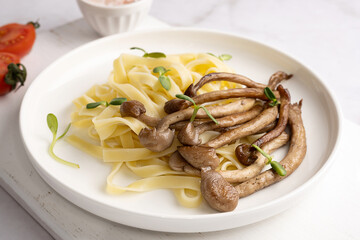 Fried mushrooms with pasta, shimeji and noodles on plate.