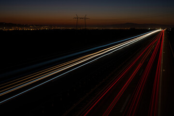 Cars light trails on a straight highway at sunset. Night traffic trails, Motion blur, Night city road with traffic headlight motion.