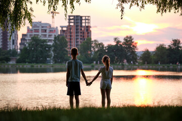 Happy siblings standing together looking at building under construction. Young children brother and sister relaxing outdoors dreaming about their future home. Family love and relationship concept