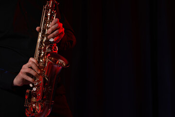 Fototapeta premium Man with saxophone on dark background, closeup. Space for text