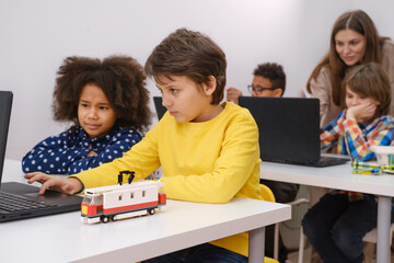 Kids learning coding, science and technology at school class. African American and Caucasian...