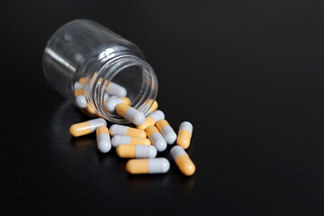 Pills on a dark wooden table, medication in capsules scattered from a bottle. Background for pharmacy, antibiotics, vitamins