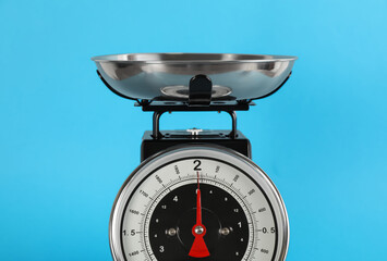 Retro mechanical kitchen scale on light blue background, closeup