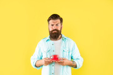unhappy mature hipster with beard holding coffee cup on yellow background, coffee