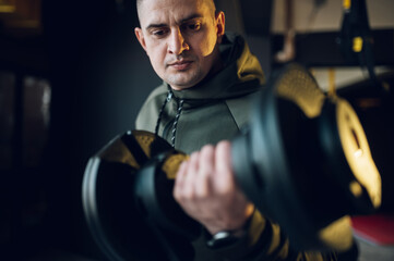Obraz na płótnie Canvas Man training in the gym and lifting dumbbells